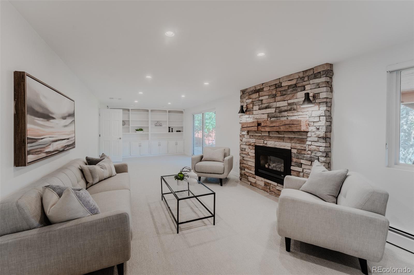 The cozy finished walkout basement is the place, featuring a stone fireplace with a charming barnwood mantel and built in shelving that creates a warm and inviting atmosphere.