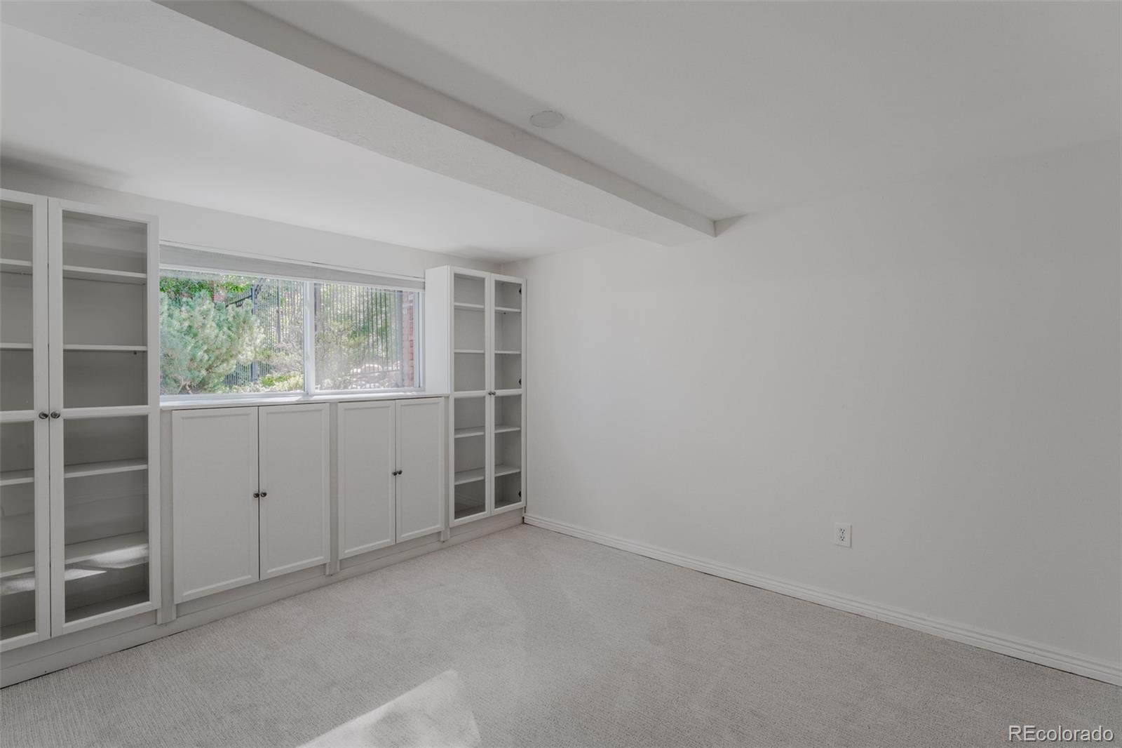 Built-in cabinets and open shelving enhance this lower level bedroom, offering ample storage and display space, making it an ideal candidate to level up to a craft room with its organized and inviting atmosphere.