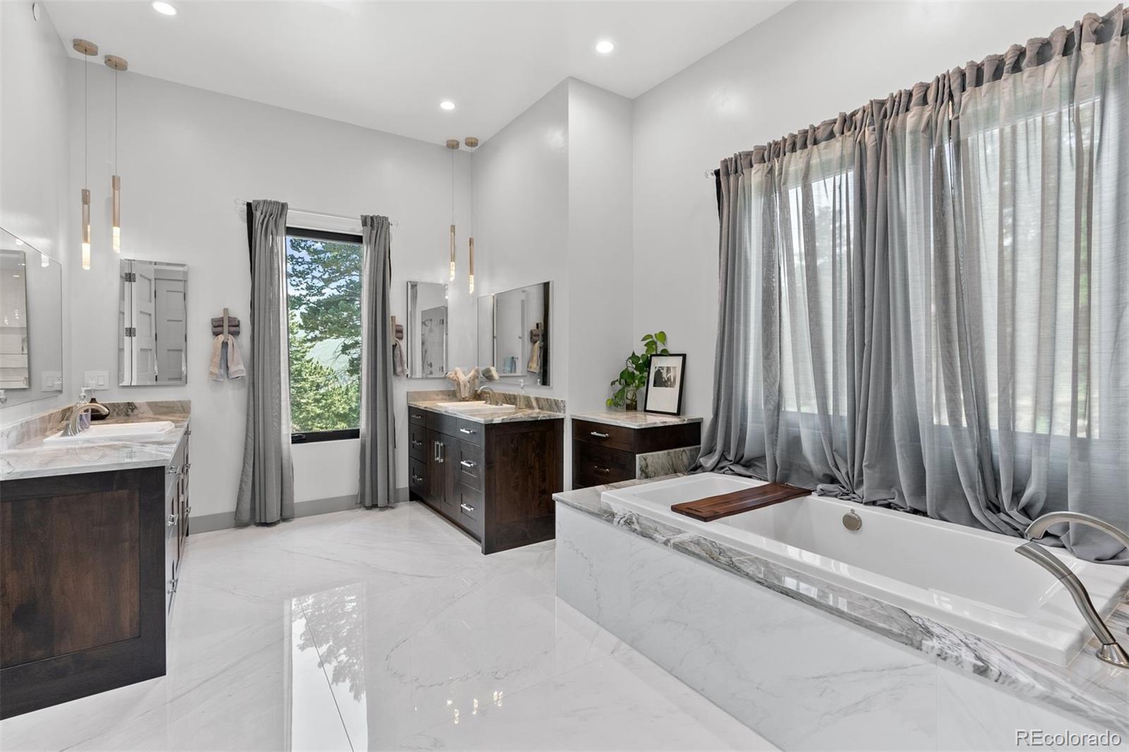 Dual Quartzite vanities and custom lighting, a soaking tub, and a glass-enclosed shower