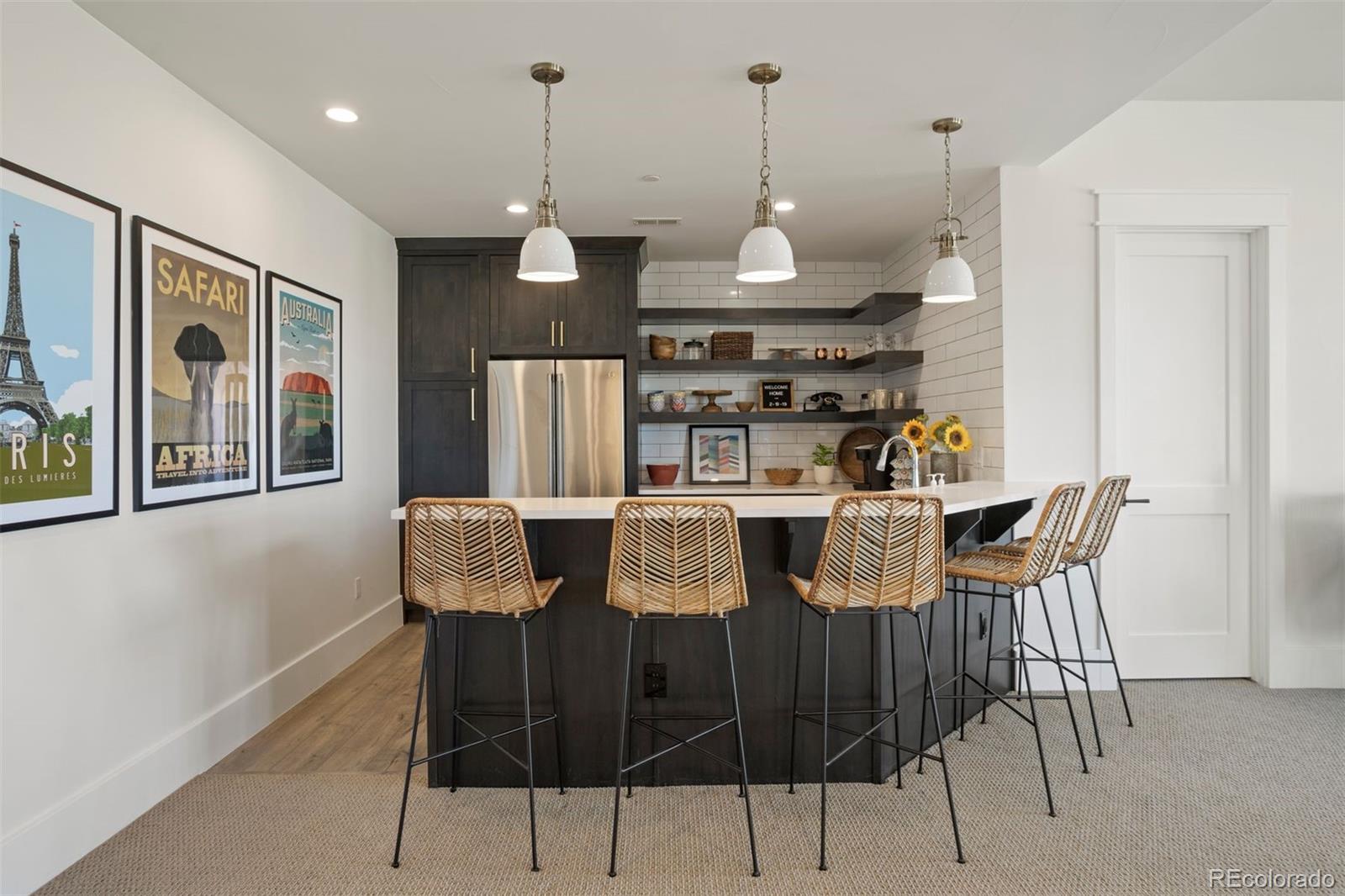 Wet bar refrigerator, dishwasher, bar top seating, and open shelving.