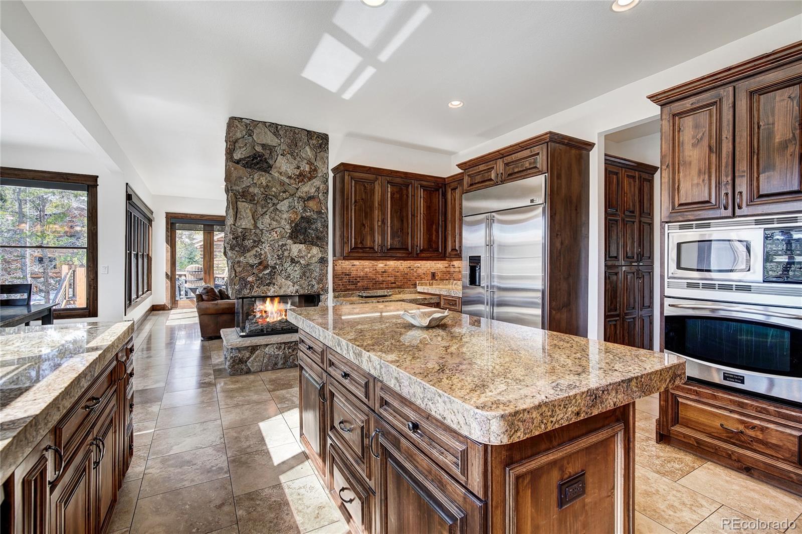 cozy peek-a-boo fireplace seen from the kitchen, dining, and main floor entertainment areas