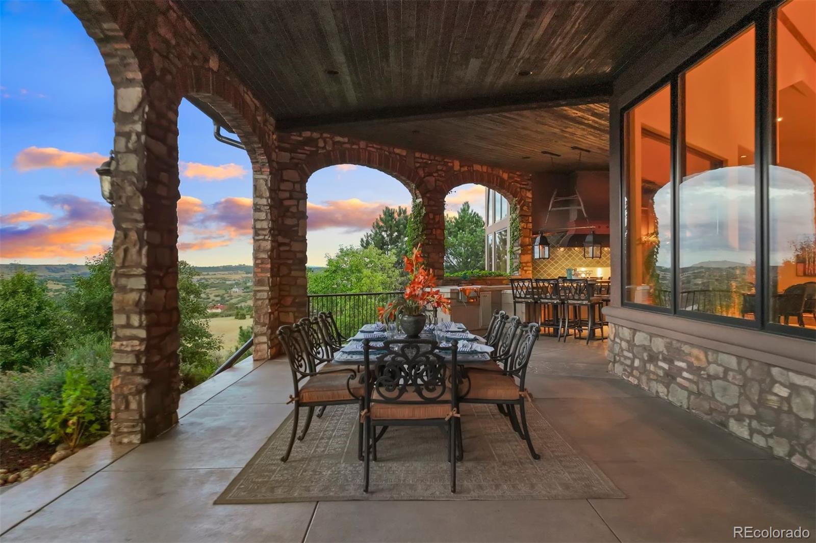 Entertain on the wrap-around covered patio with an outdoor kitchen, framed by vine-draped walls and archways.