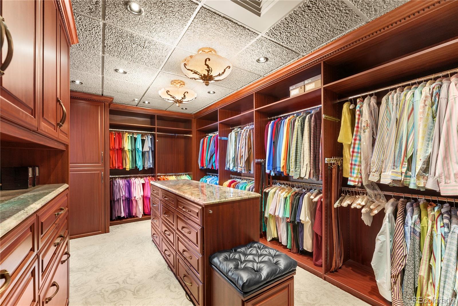 Primary walk-in closet with built-in custom cherry wood cabinetry and drawers