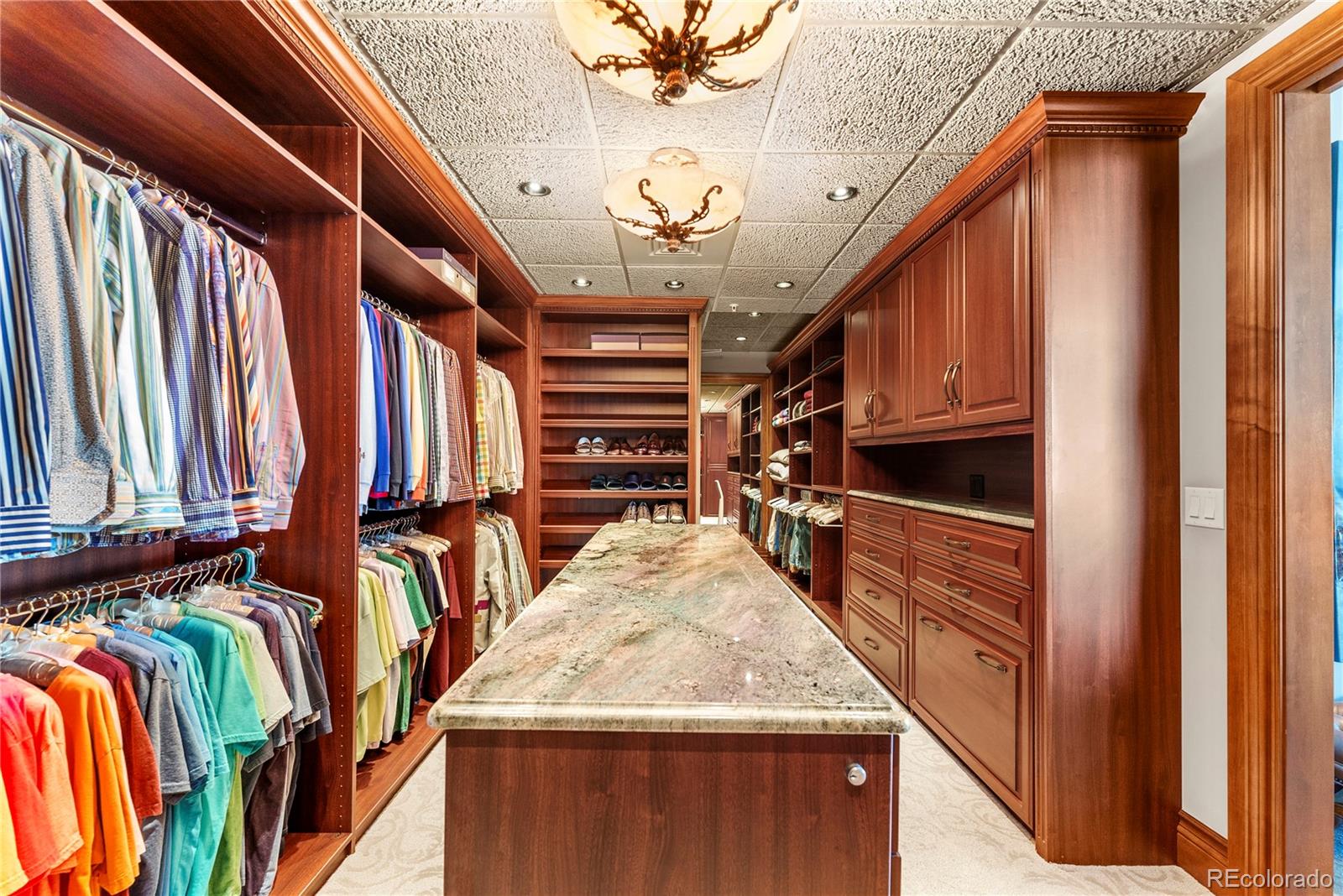 Primary closet with island and hidden fire escape door to stairs