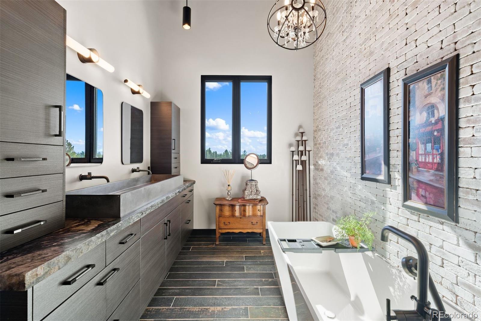 Primary bathroom with freestanding tub, walk-in shower with multiple shower heads, and a 60-inch concrete trough sink with ample storage.