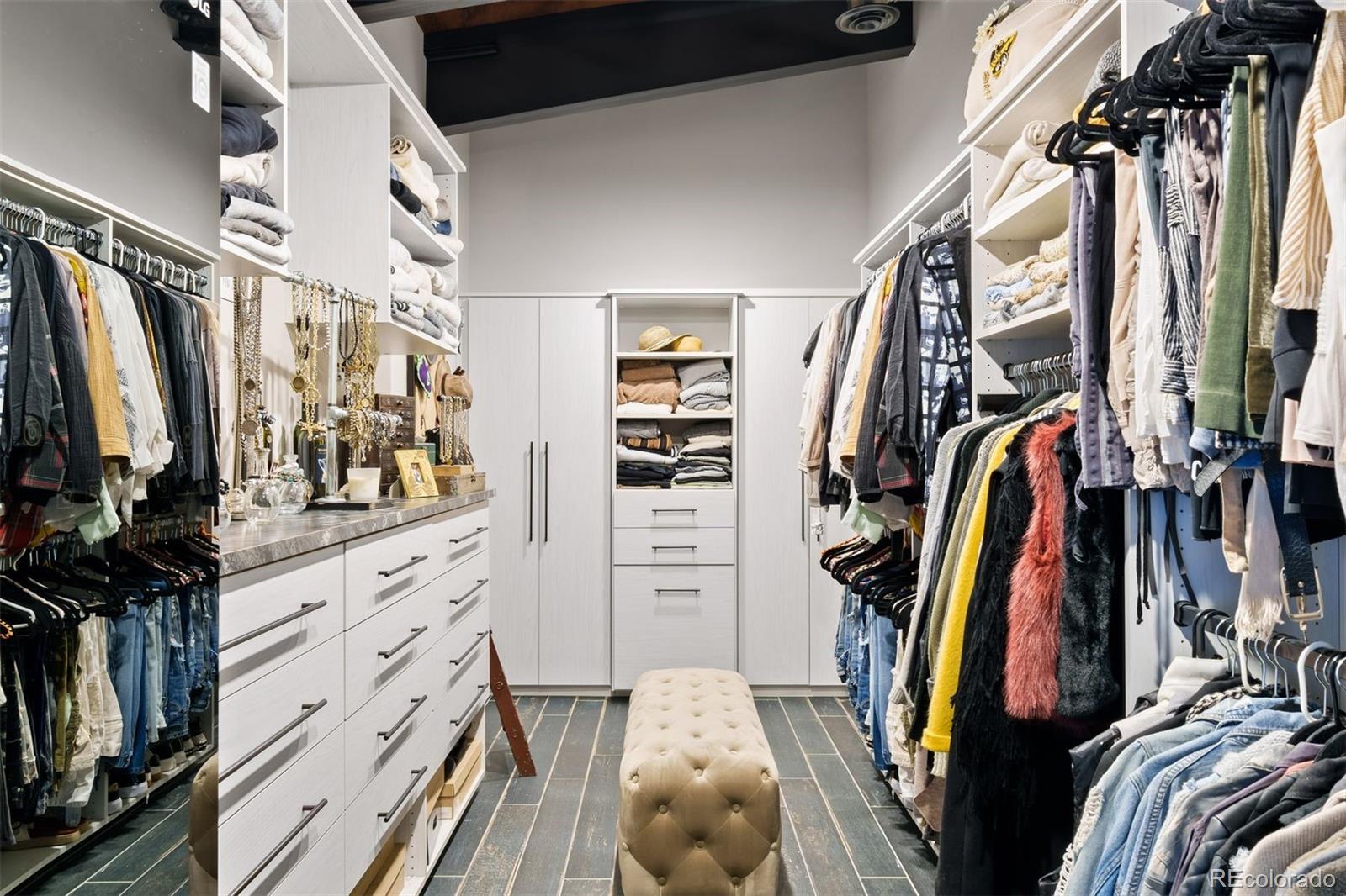 Dual primary walk-in closets with custom organization systems, one is massive with a clothes steamer, and the other has a Miele® stacked washer and dryer.