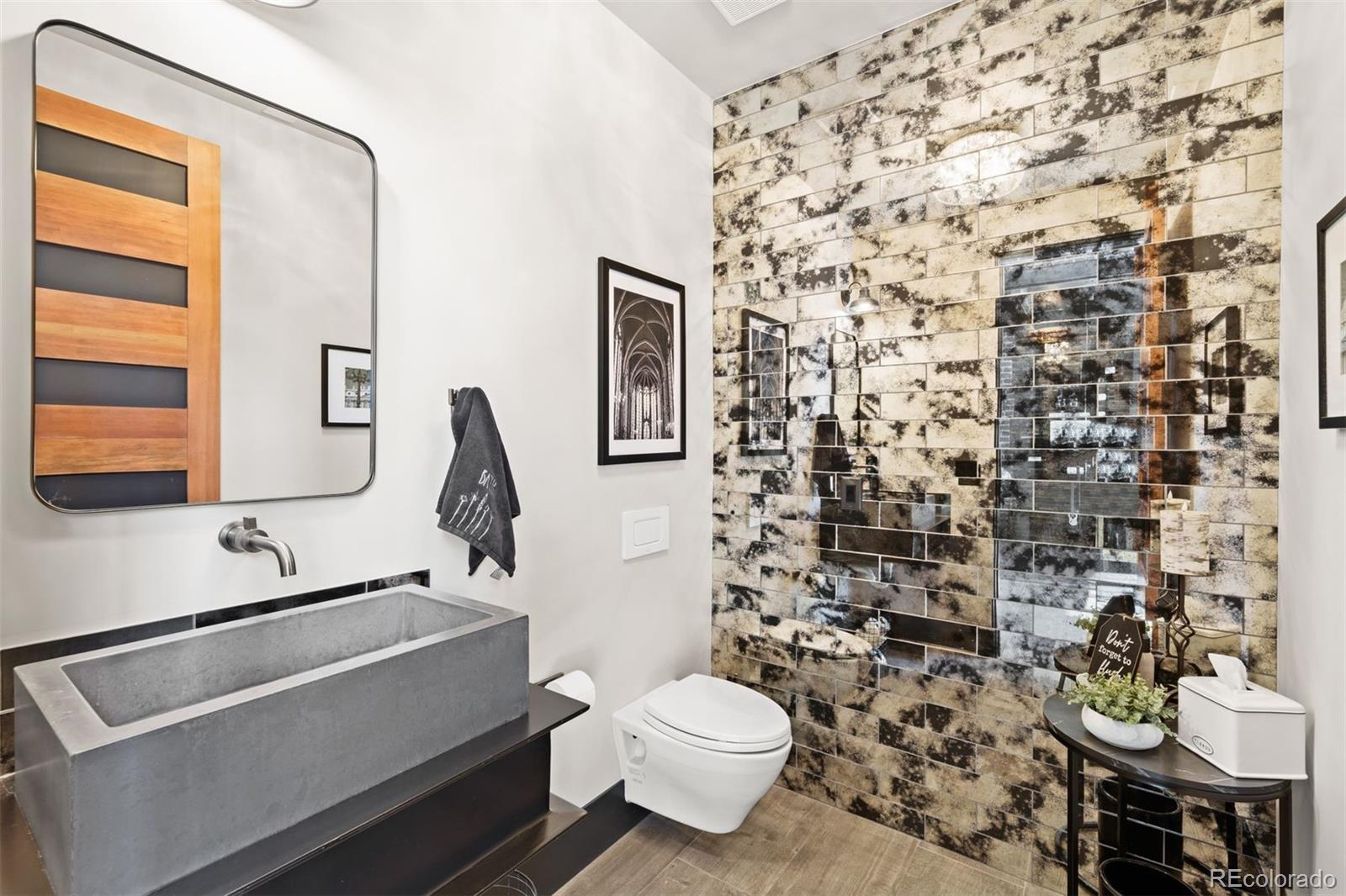 Powder bathroom off great room with smoked mirrored tile accent wall.