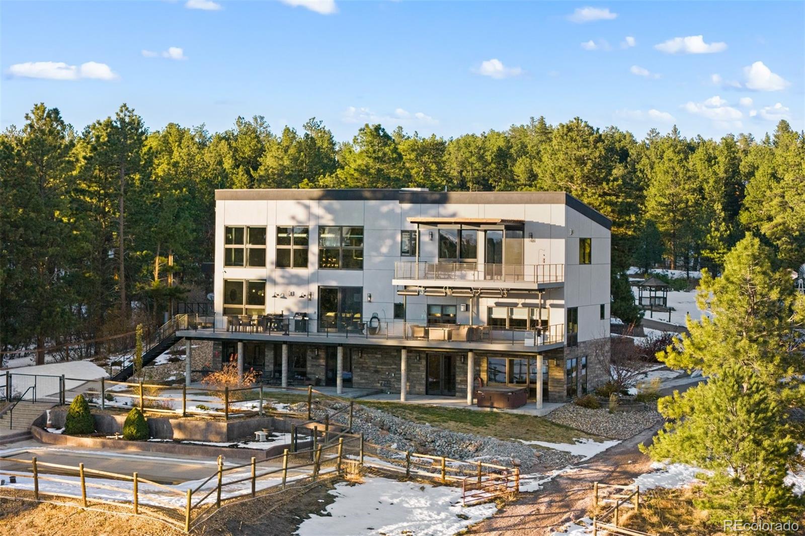 Fantastic outdoor living with a full-length deck featuring a heated pergola, a lower covered patio with a hot tub, and an in-ground pool.