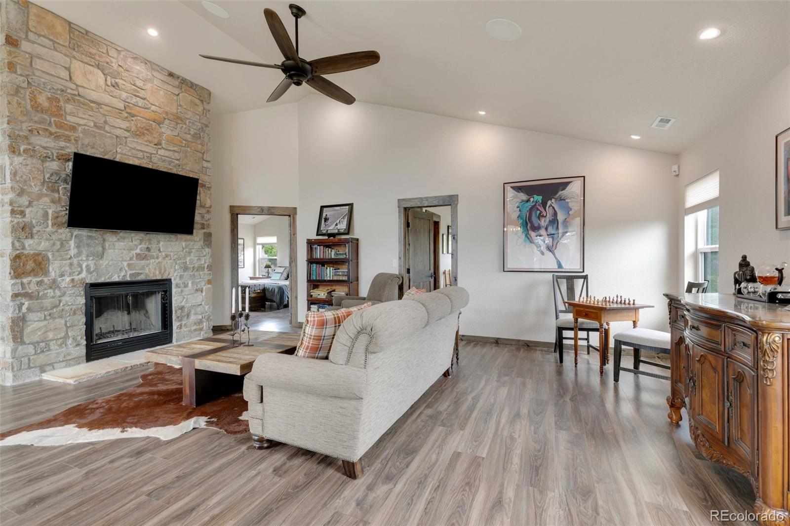 Barn living room has wood burning fireplace with natural stone, and 14 ft ceilings.