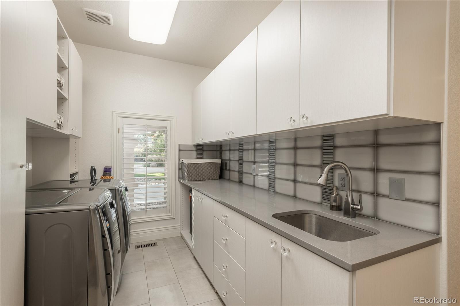 Main level laundry room with sink and ample cabinet space.