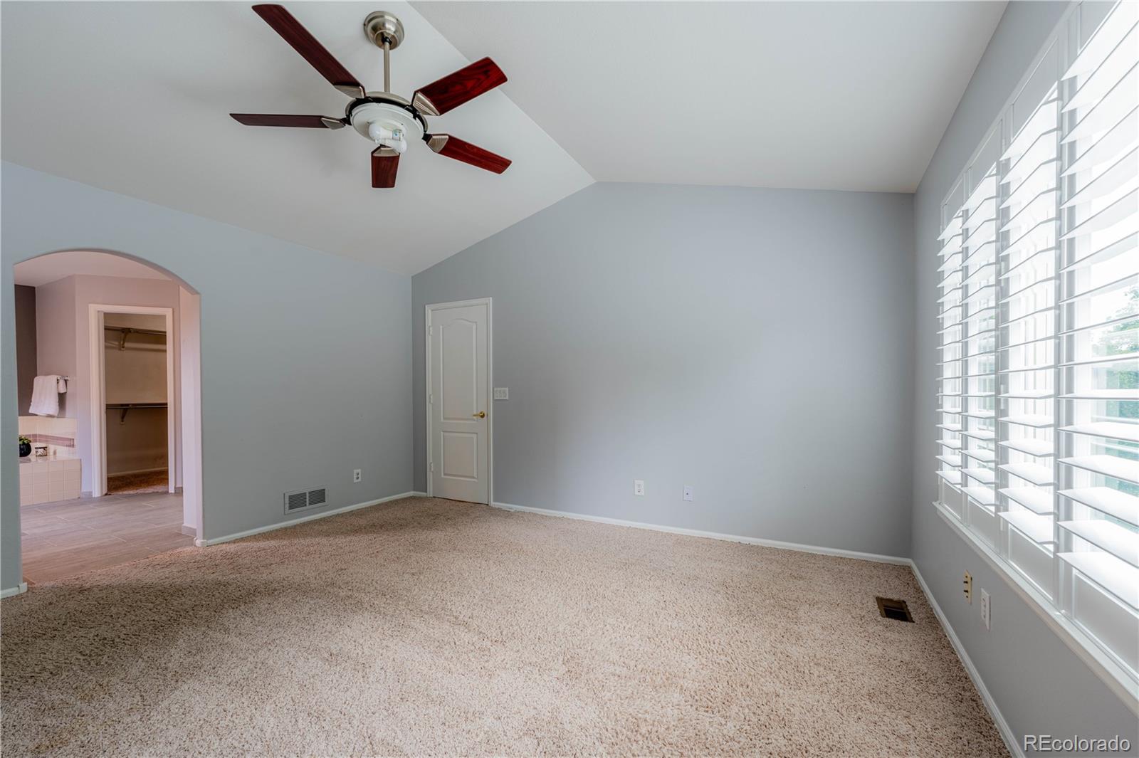 Primary bedroom with vaulted ceiling, plantation shutters and en suite bathroom