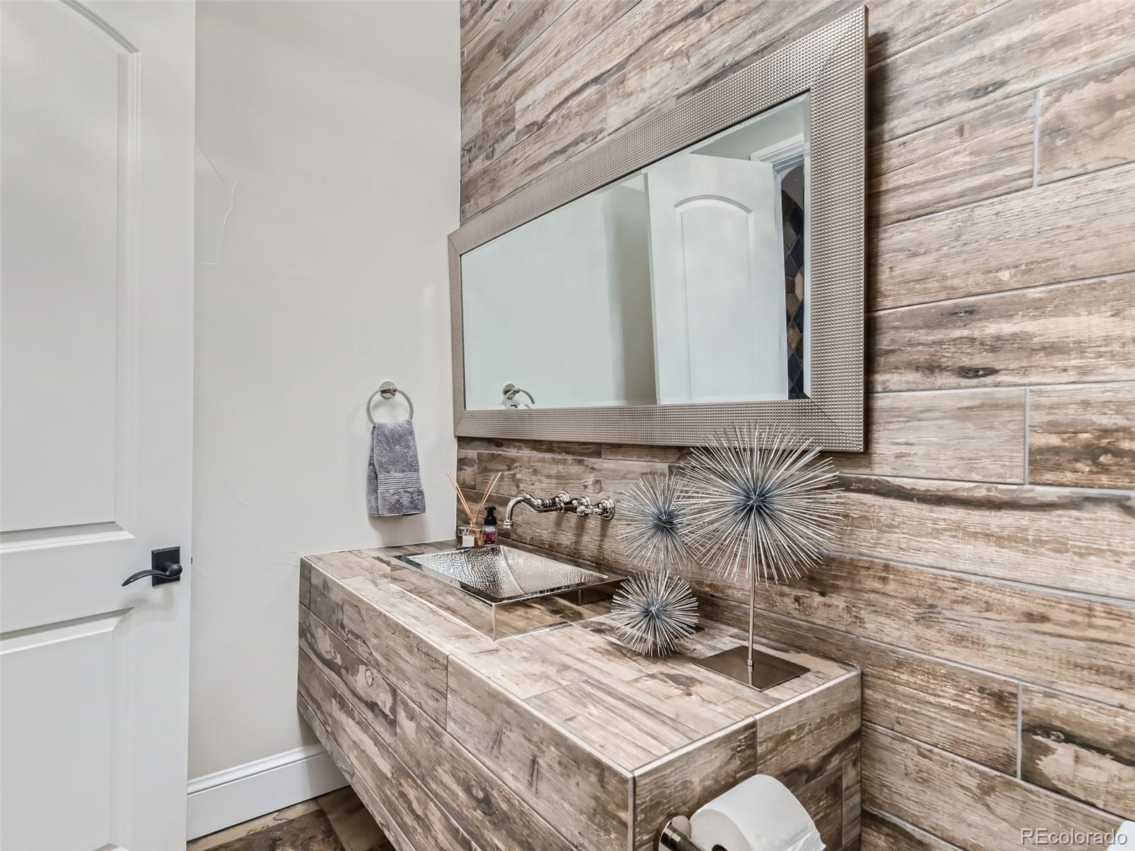 Main level guest half bath featuring a tile accent wall.