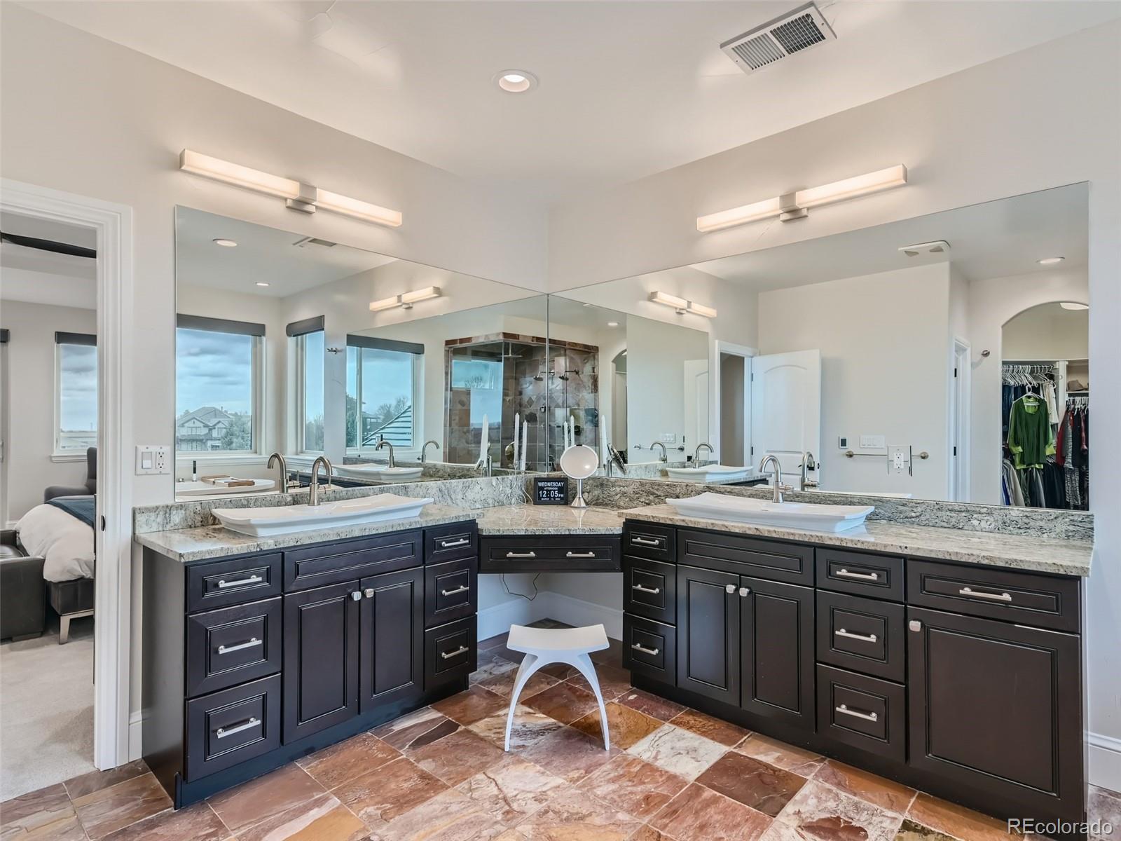 Luxurious primary bath has a spa-like atmosphere with free standing soaking tub, huge walk-in steam shower with multiple shower heads, heated floors, dual vanities, and separate makeup vanity area.