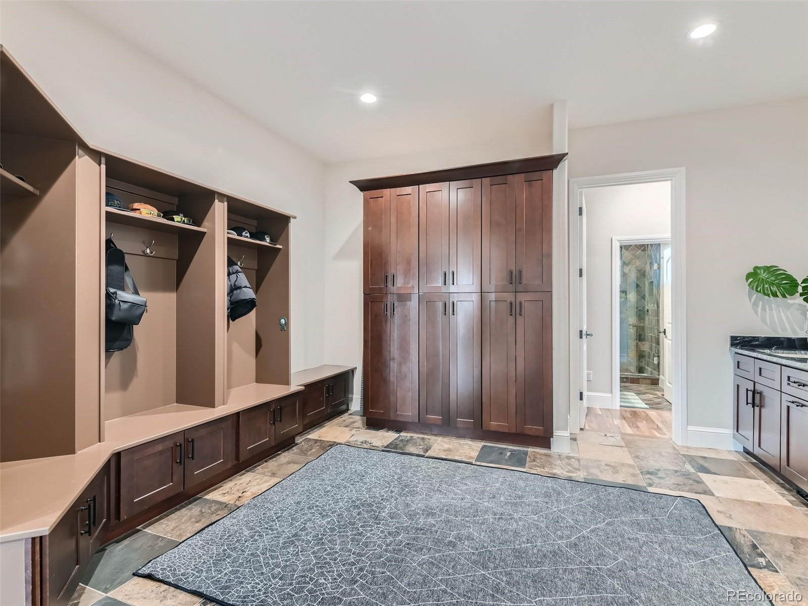 Oversized mudroom and laundry room next to garage has built-in storage cubbies, sink, water fountain, and dog wash station.