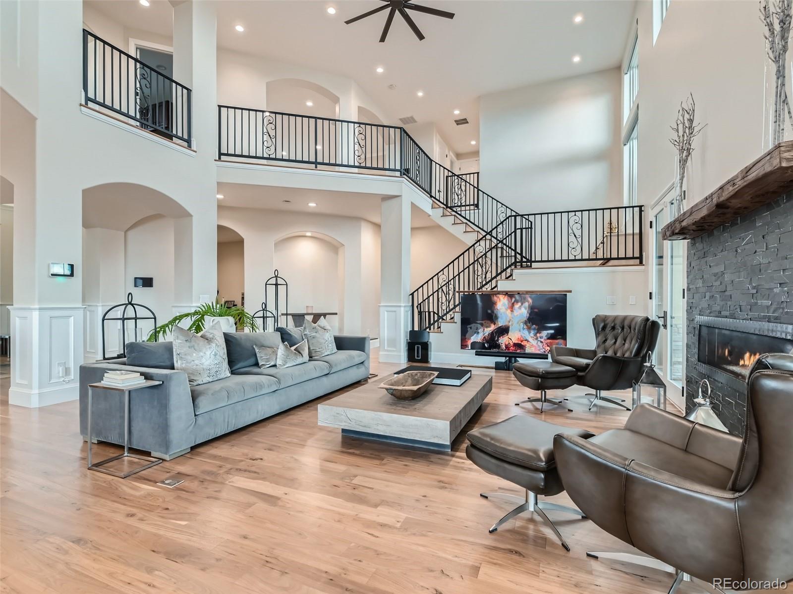 Great room has dramatic two-story ceiling, walnut hardwood floors, linear fireplace, hidden pop-up under floor tv lift, Lutron blinds, lights, Sonos sound system, wall of glass doors opening to an extensive outdoor area.