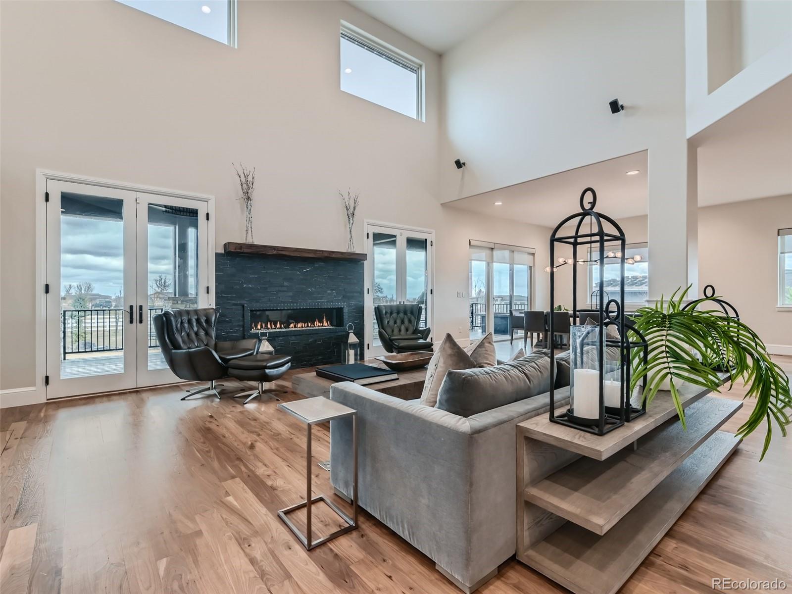 Great room has dramatic two-story ceiling, walnut hardwood floors, linear fireplace, hidden pop-up under floor tv lift, Lutron blinds, lights, Sonos sound system, wall of glass doors opening to an extensive outdoor area.