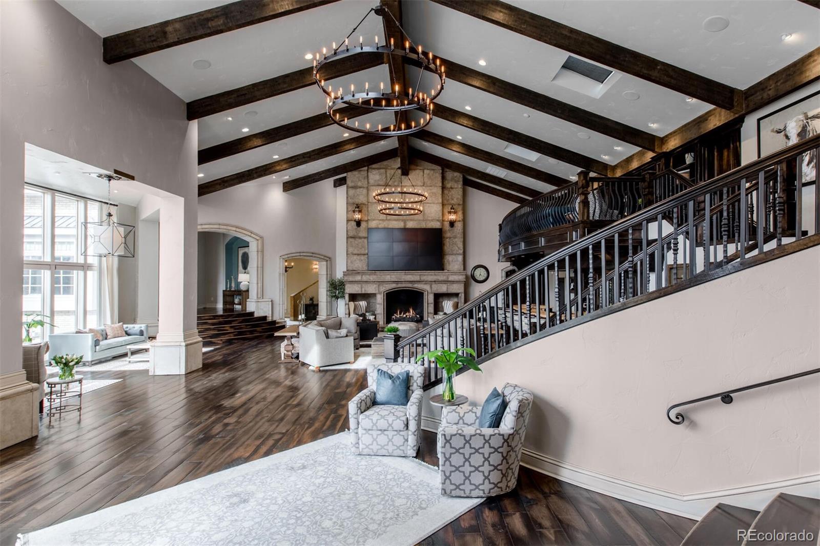 Among these are the jaw-dropping vaulted and beamed Great Room with soaring 20 foot floor-to-ceiling fireplace, walls of windows, wine tasting nook, expansive wood and travertine topped bar, phenomenal designer lighting including double iron chandeliers.