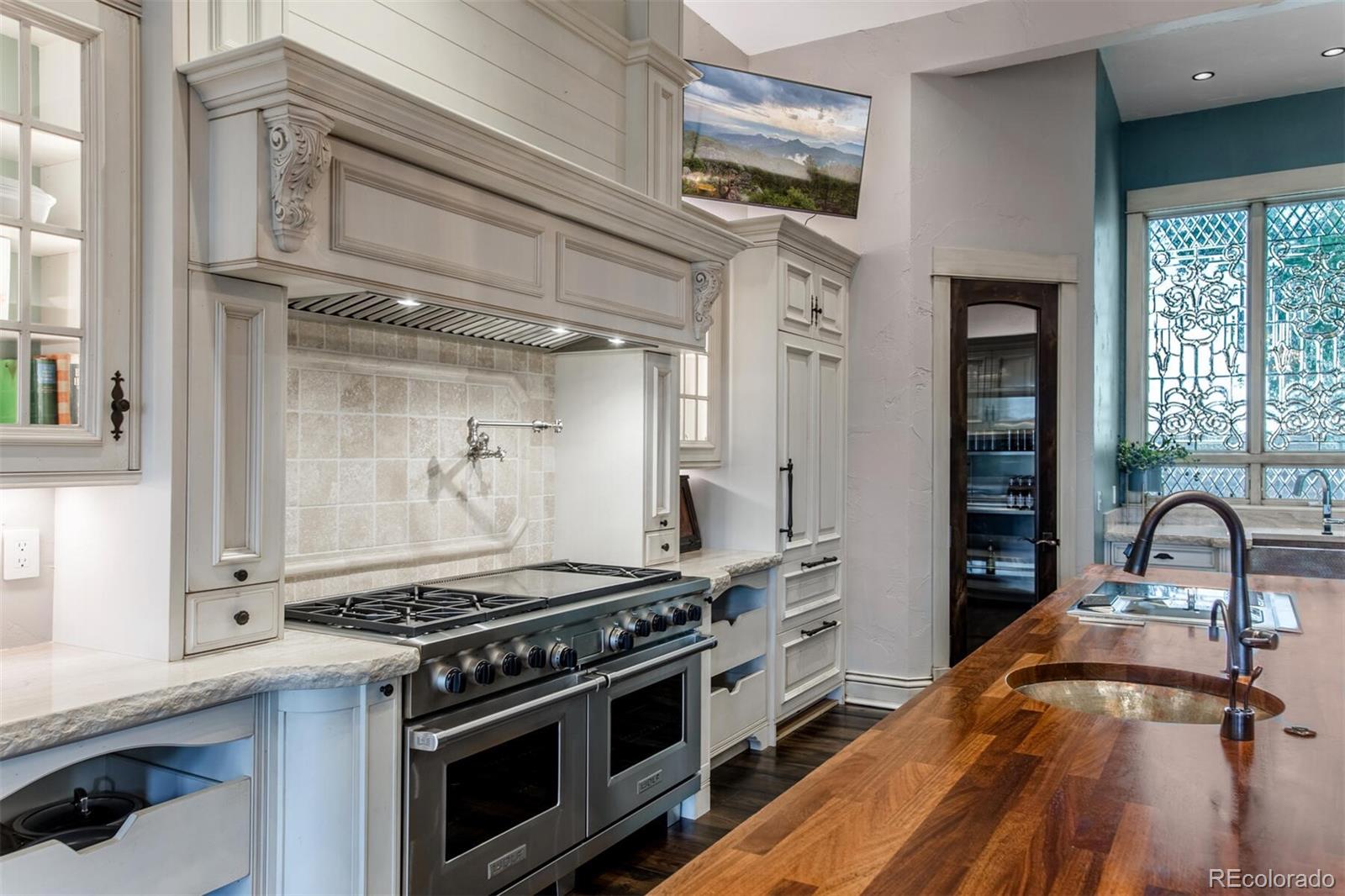 In addition to the walk-in refrigerator, there is a custom refrigerator and freezer to the left, pot filler over the stove and dual Wolf ovens. On the island, copper sinks with instant filtered hot/cold water as well as a pasta/warming station.