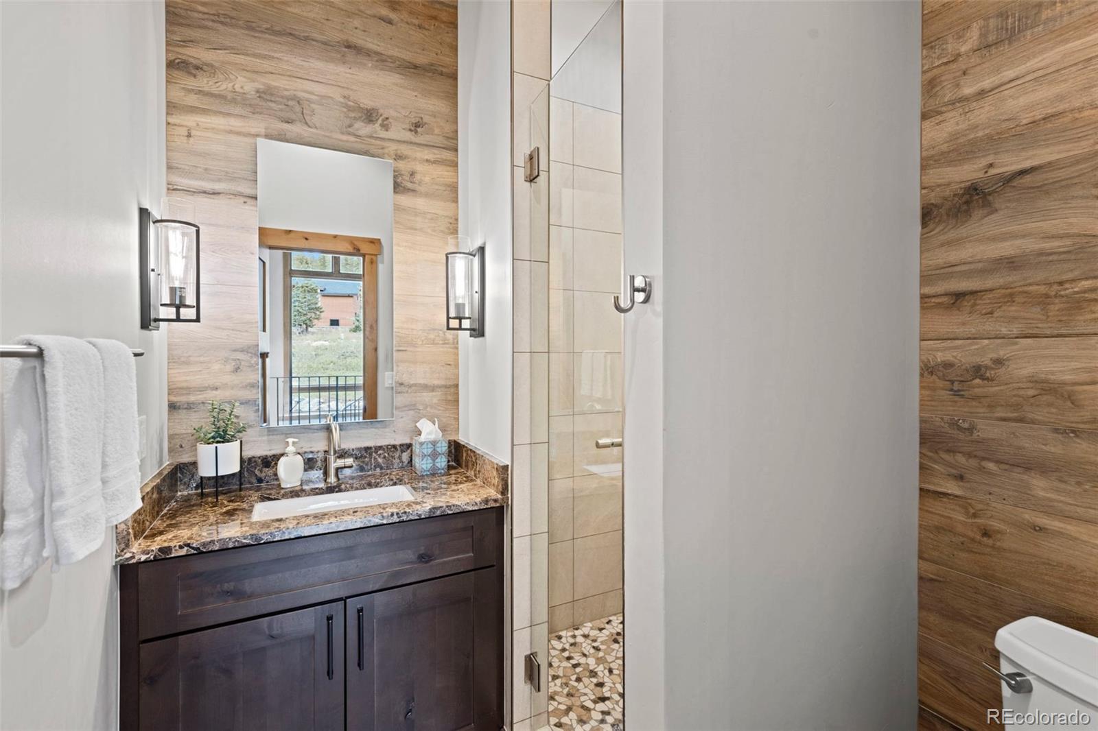 Powder room with beautiful wood look tile and a pebble shower floor