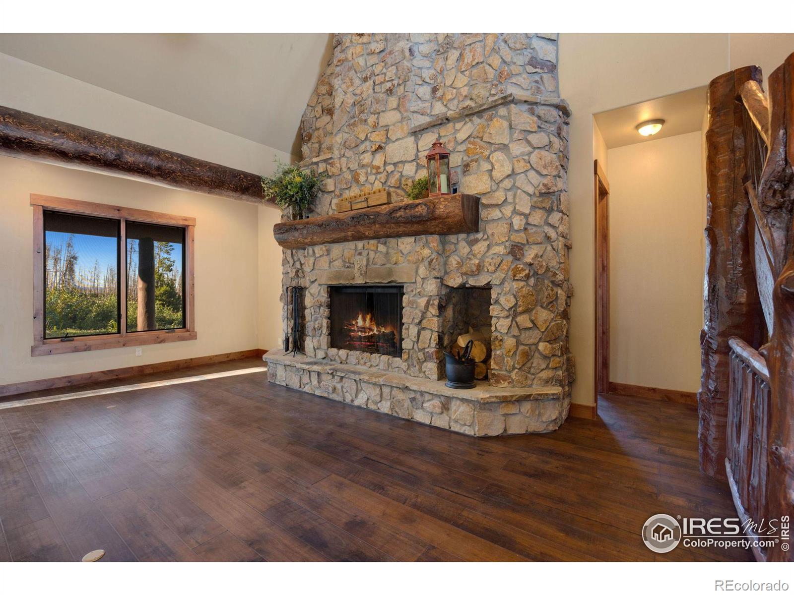 Custom floor to ceiling fireplace, surrounded by large windows, complete with logs and stone harvested from the property