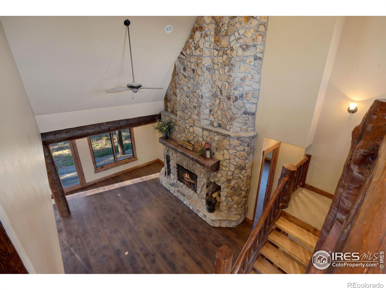 Balcony view of the floor to ceiling fire place, custom log staircase and high ceilings