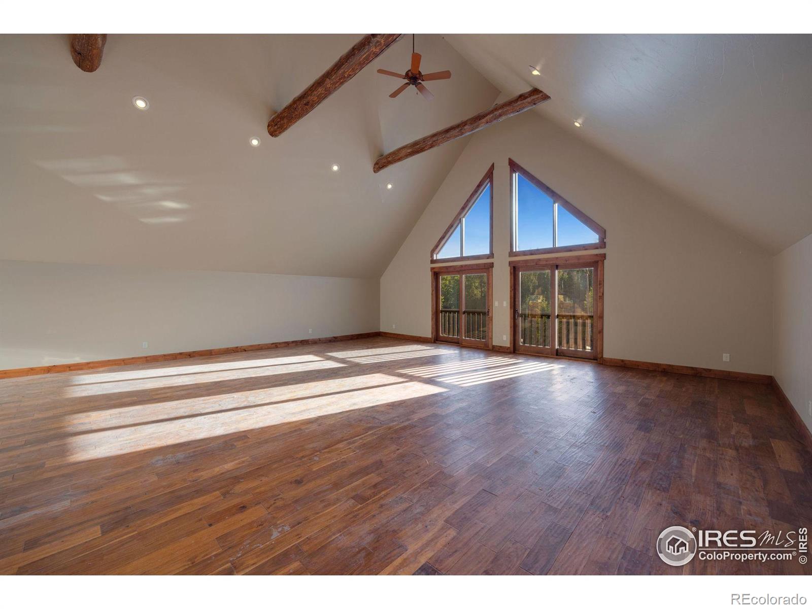 Large greatroom with ceiling fans, sliding glass for natrual air movement and catching the sounds of the outdoors that echo through the large vaulted ceilings, additional wet bar and refrigerator out of view but positioned on the left side of the room