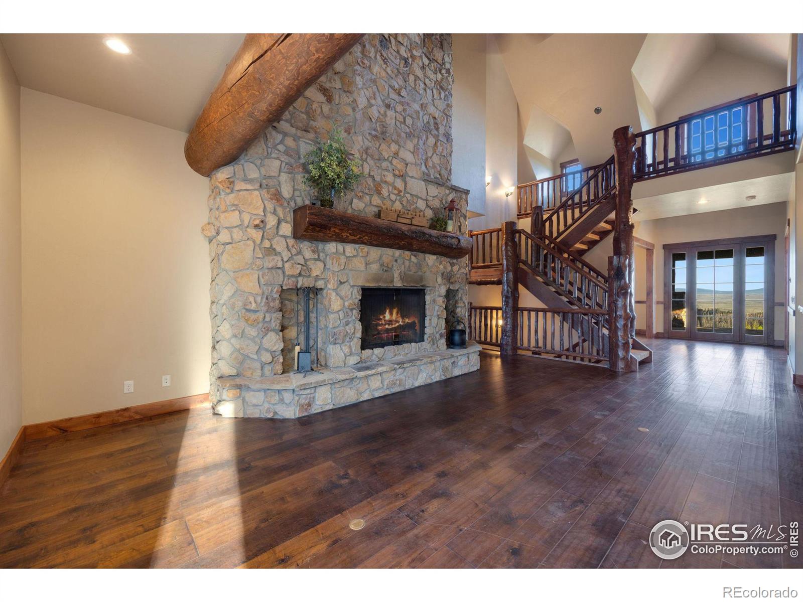 Large vaulted ceilings over the foyer and living room lead to the custom floor to ceiling fireplace complete with stones harvested from the land and in floor heating