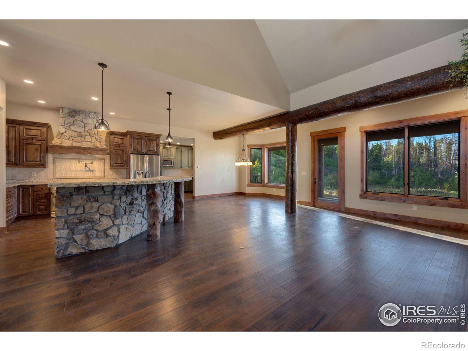 View of large kitchen, breakfast dining area, custom logs from the land, with large windows for plenty of natural light, and views of the fire pit