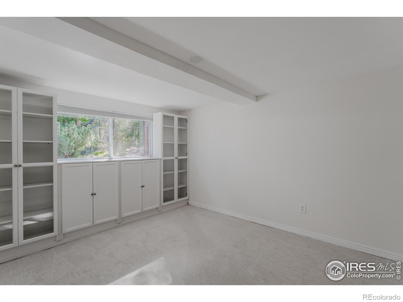 Built-in cabinets and open shelving enhance this lower level bedroom, offering ample storage and display space, making it an ideal candidate to level up to a craft room with its organized and inviting atmosphere.