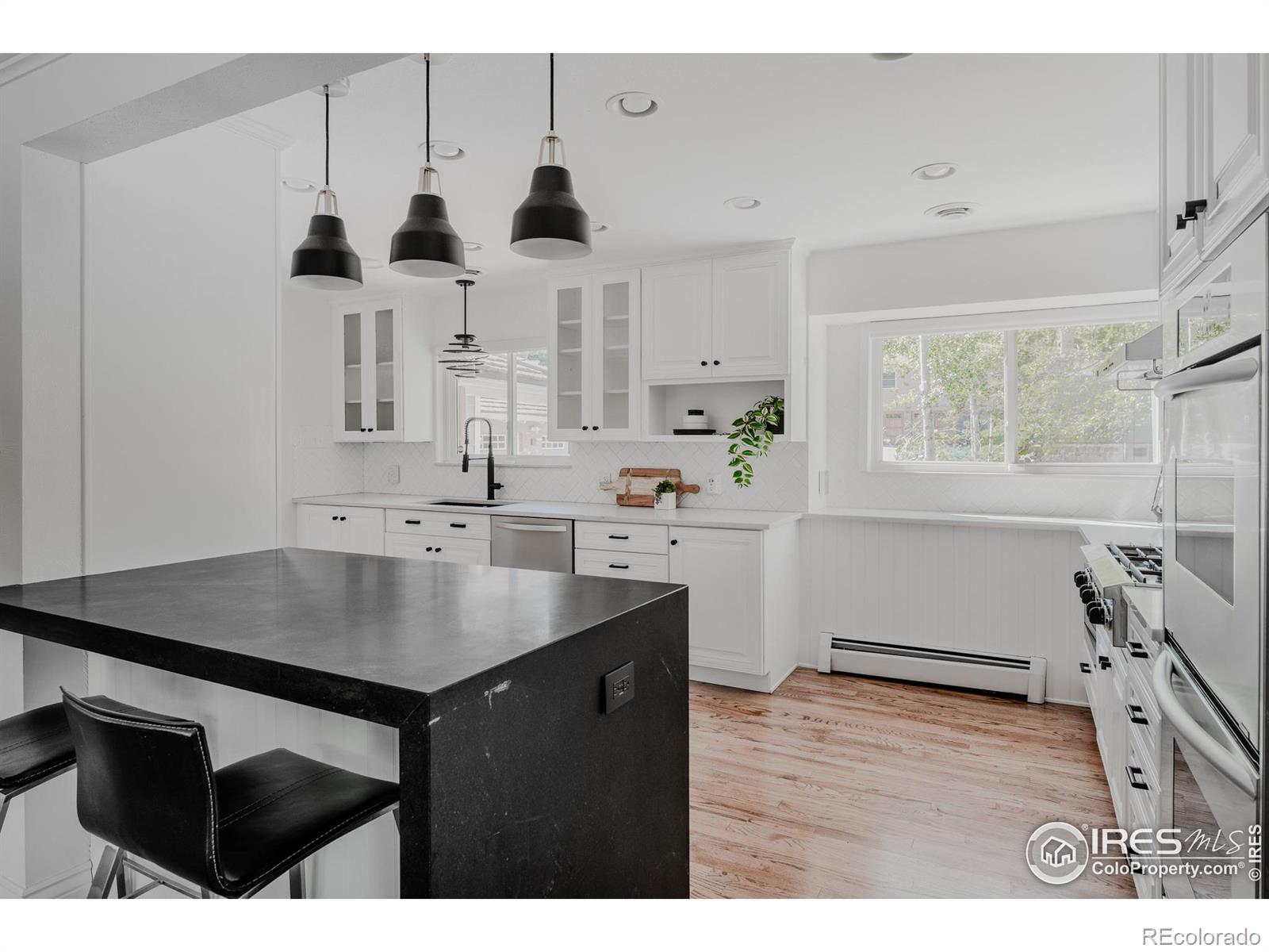 Bold, contrasting black fixtures provide a striking accent, while the substantial honed black quartz waterfall peninsula, paired with stylish light fixtures, elevates the spaces sophistication.