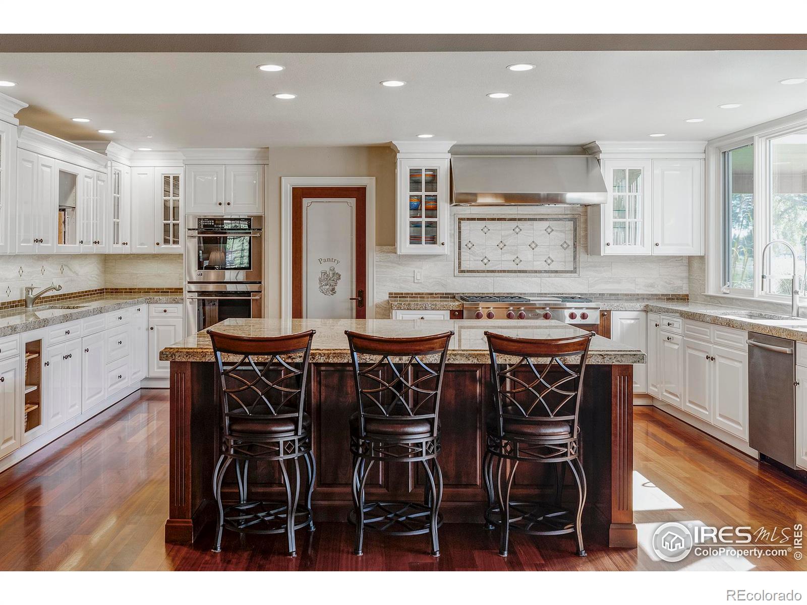 The spectacular kitchen awaits your next culinary achievement with rows of custom cabinetry, granite countertops & upscale stainless steel appliances, including a vented six-burner Wolf cooktop with a griddle, two wall ovens, a side-by-side refrigerator.