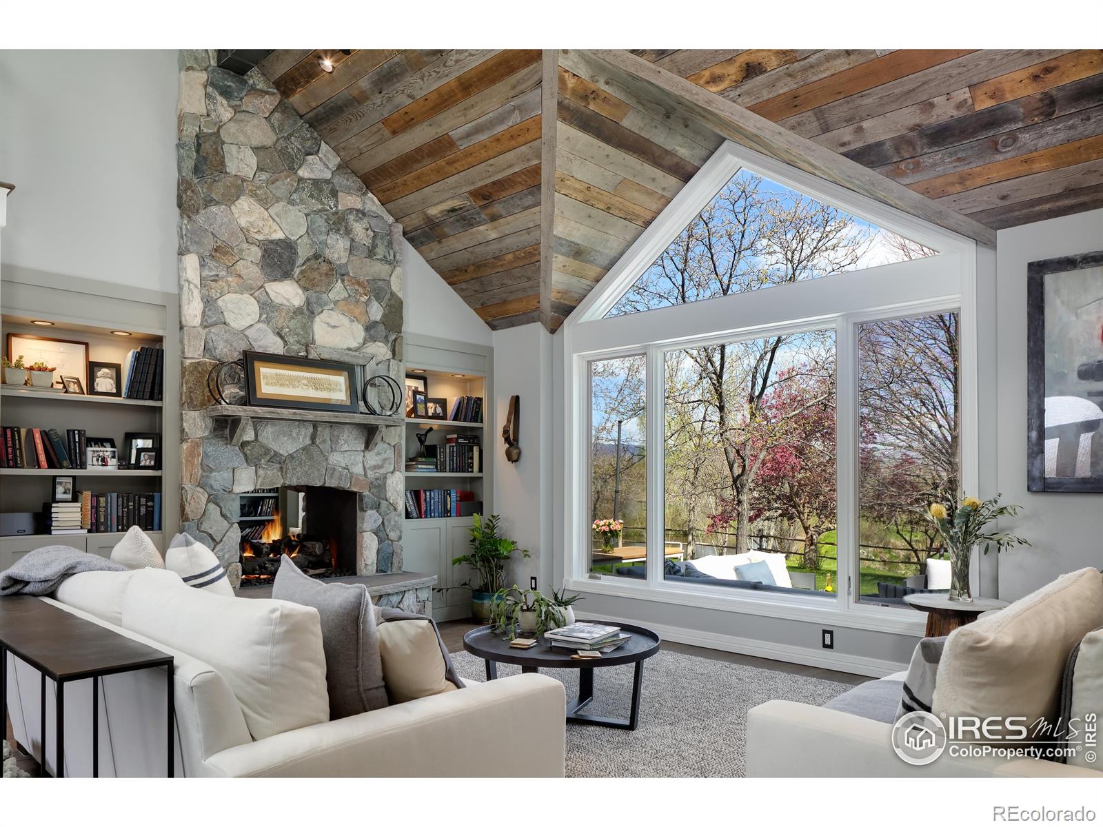 Vaulted, reclaimed barnwood ceiling w/ skylights, Isokern see through fireplace and sparkling lake views across the back patio