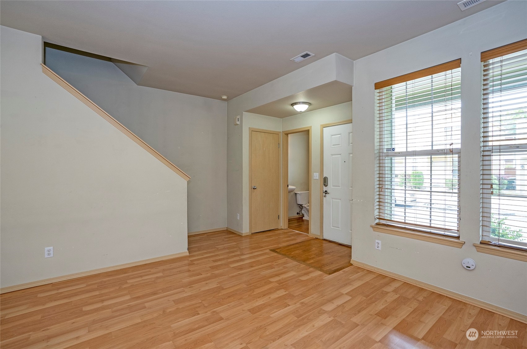 The living area offers a view toward the entry, highlighted by large windows that fill the space with natural light. The conveniently located powder room on the lower level adds to the home's functionality.