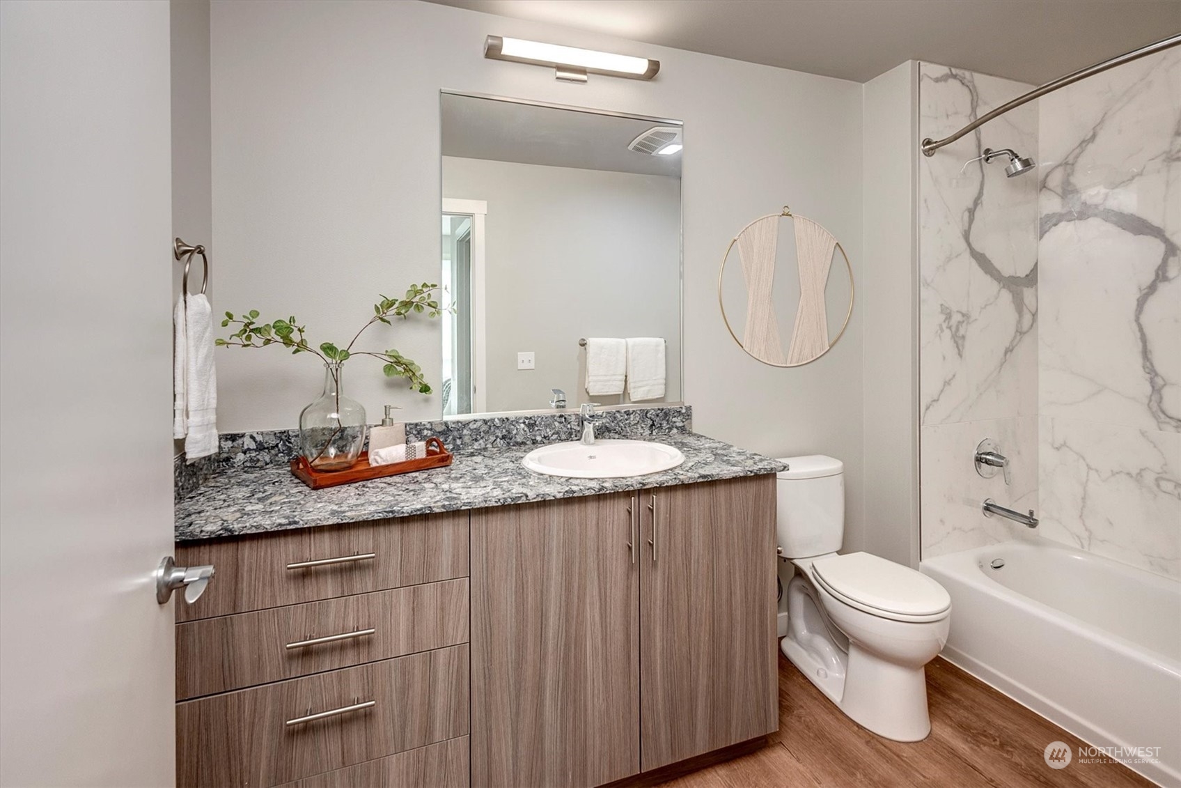 Complemented by a lavish bathroom with a spacious vanity, ceramic walls surrounding the tub,