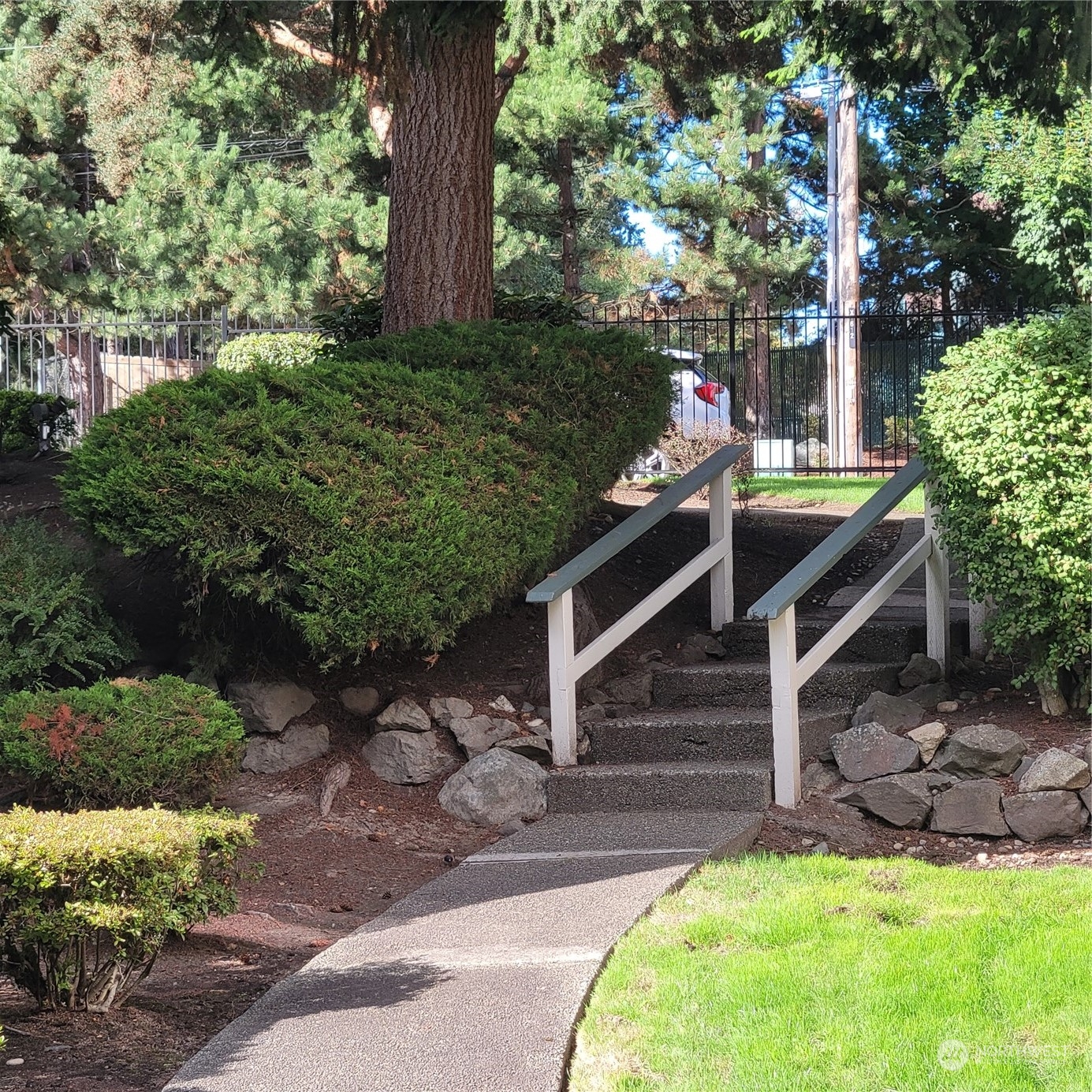 Stairs heading toward front of complex by pool area. Attractive, elegant iron fencing.