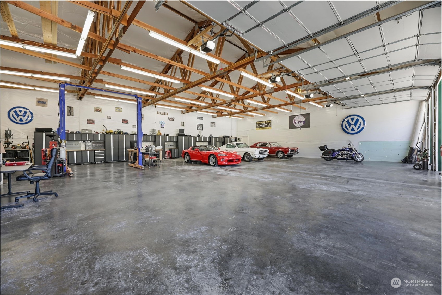 This space is HUGE. Big enough it makes the 3 cars & motorcycle look so small! Car lift and multiple new work spaces with full cabinets & benches.