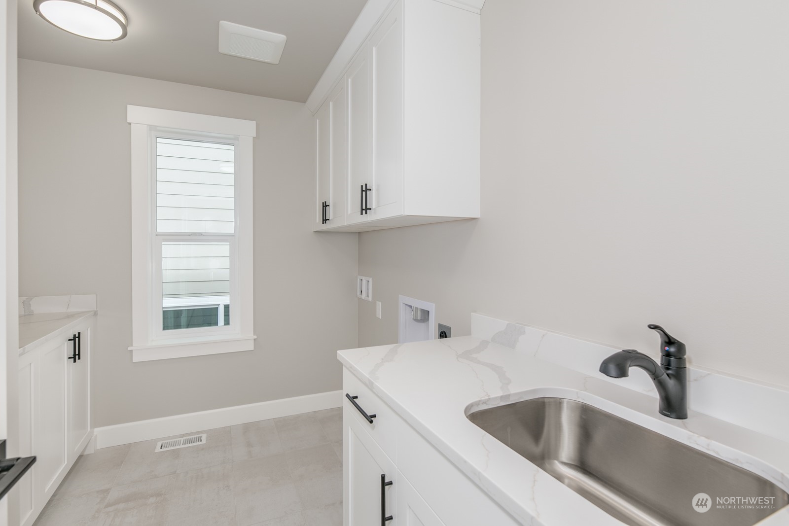 Huge laundry room is complete with a sink, cabinets, several counters and an opening window for fresh air.