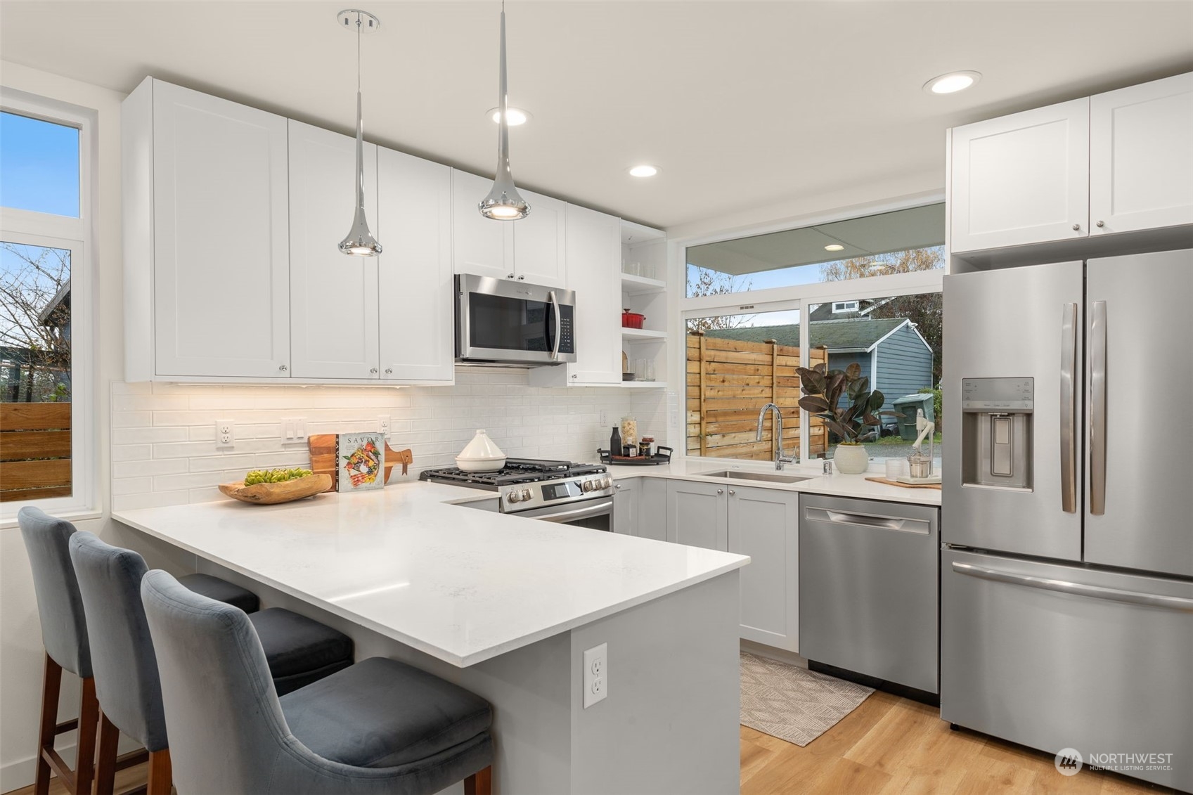 Pristine quartz countertops, a breakfast bar, and sleek cabinetry create a chef’s dream in this kitchen.