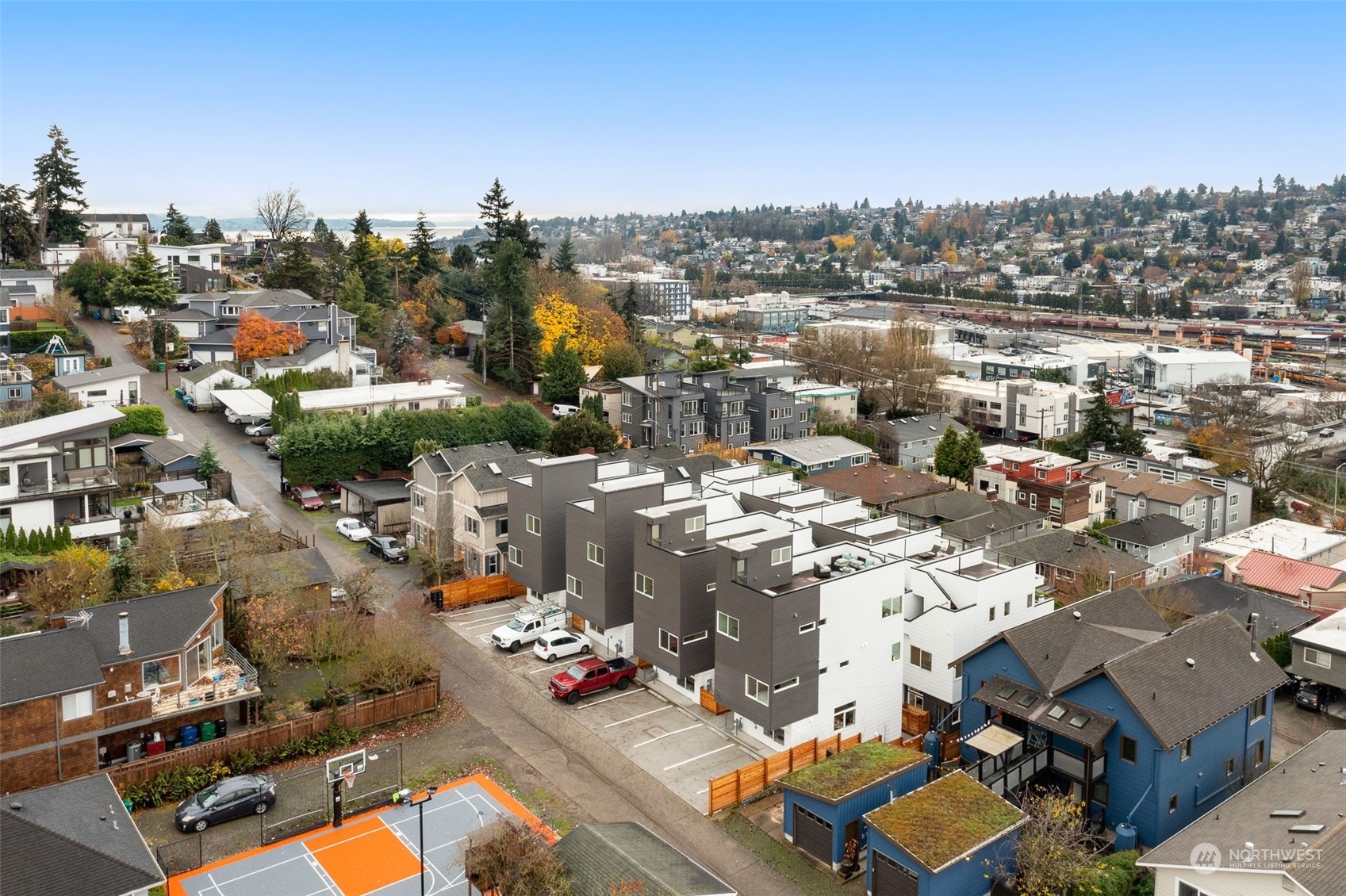 Capturing the vibrant community with a peek at neighboring homes and amenities, including a basketball court, green spaces, and a lively urban backdrop.