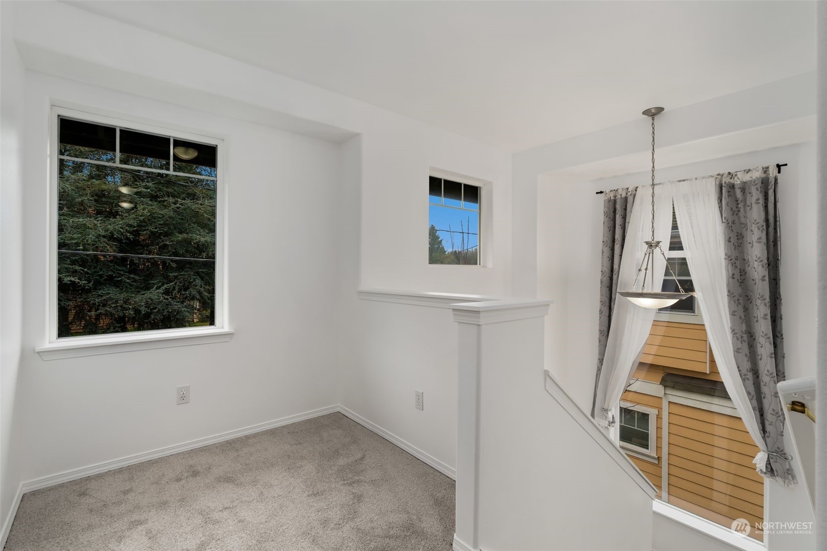 Bright and inviting second-floor landing with large windows, soft carpeting, and an open layout, perfect for a reading nook or additional decor.