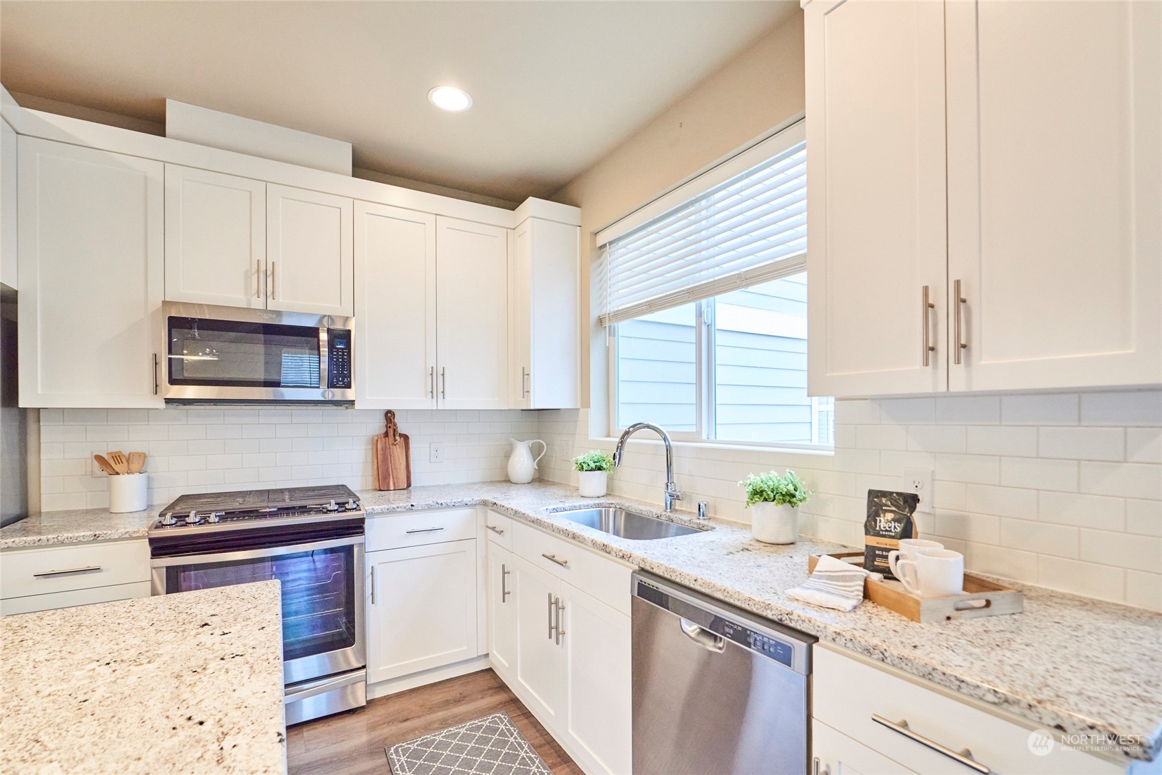 The modern kitchen complete with slab granite countertops, soft close drawers, undermount sink, 5 burner gas stove, stainless steel appliances and a kitchen island.