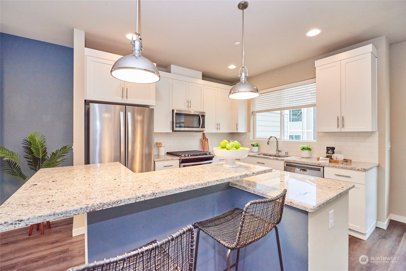 A multi-level slab granite kitchen island with breakfast bar, pendant lamps and lots of storage is a "rare find" in a townhome!