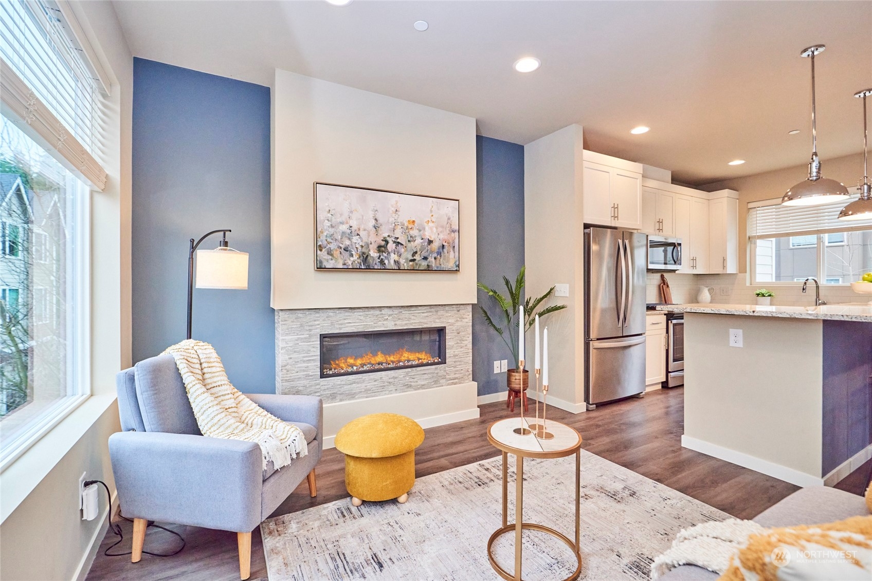 The open concept living room features an electric fireplace, luxury vinyl planked floor, designed paint colors, recessed lighting and a huge window for wonderful natural light.