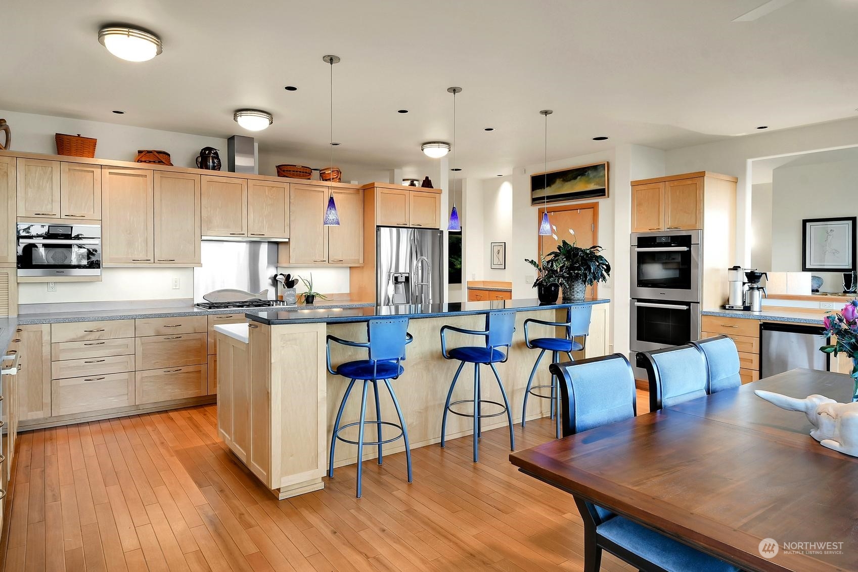 Spacious counter that comfortably seats 3-4 bar stools, high-end Miele double ovens with a Bluetooth probe for precision cooking, Miele warming drawers, a wine fridge, and a 3rd sink.