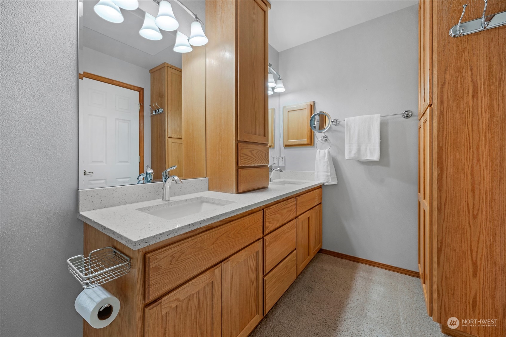 Primary Bath with dual vanity to the right with quartz counters and inset sinks.  A glass enclosure large shower with ceramic tile flooring in front.