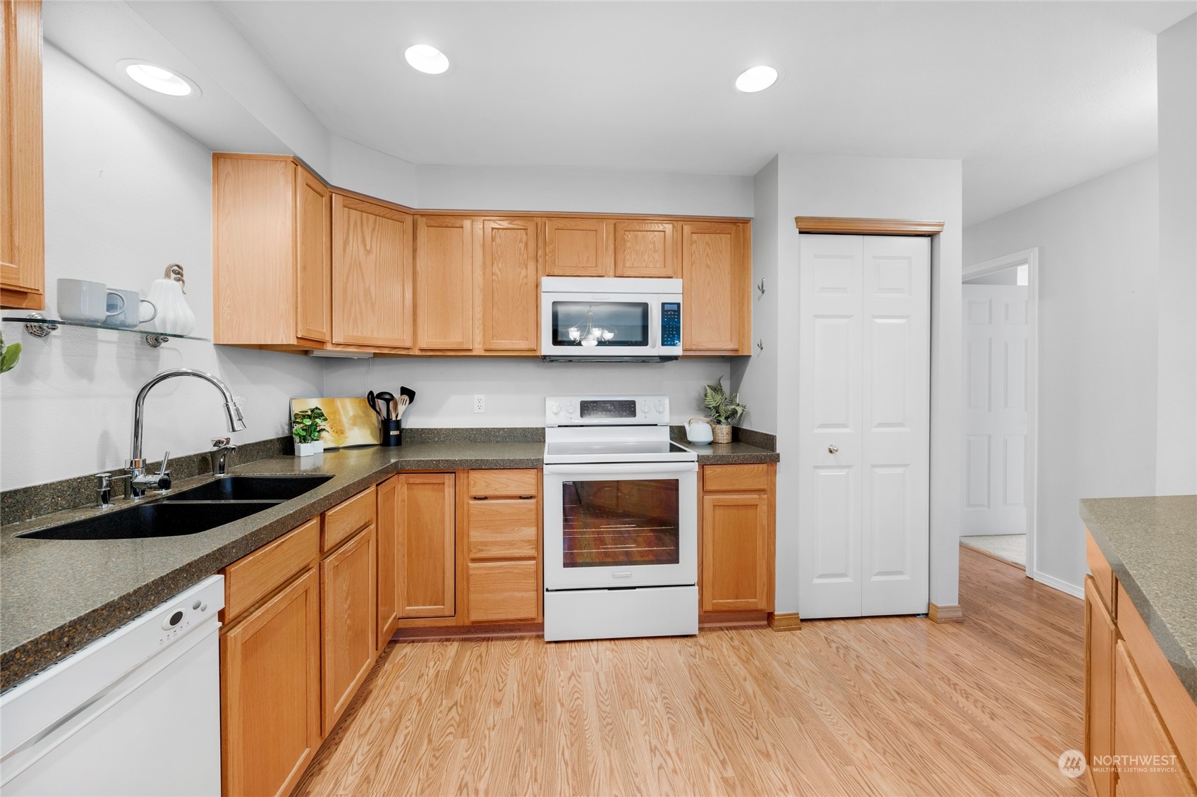 The open kitchen has plenty of space and features quartz counters, a granite composite double sink w/long noozle & hot water dispenser, and shaker oak cabinets.  A pantry closet to your right.