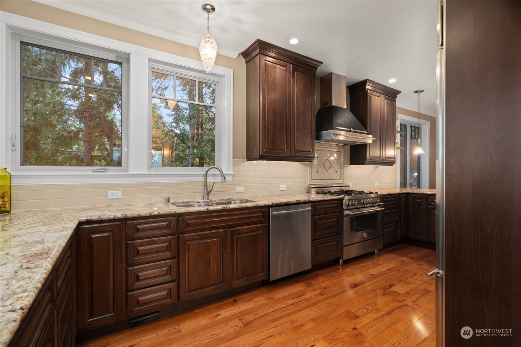 A chef's kitchen with luxurious cabinetry, marble counters and stainless steel appliances.