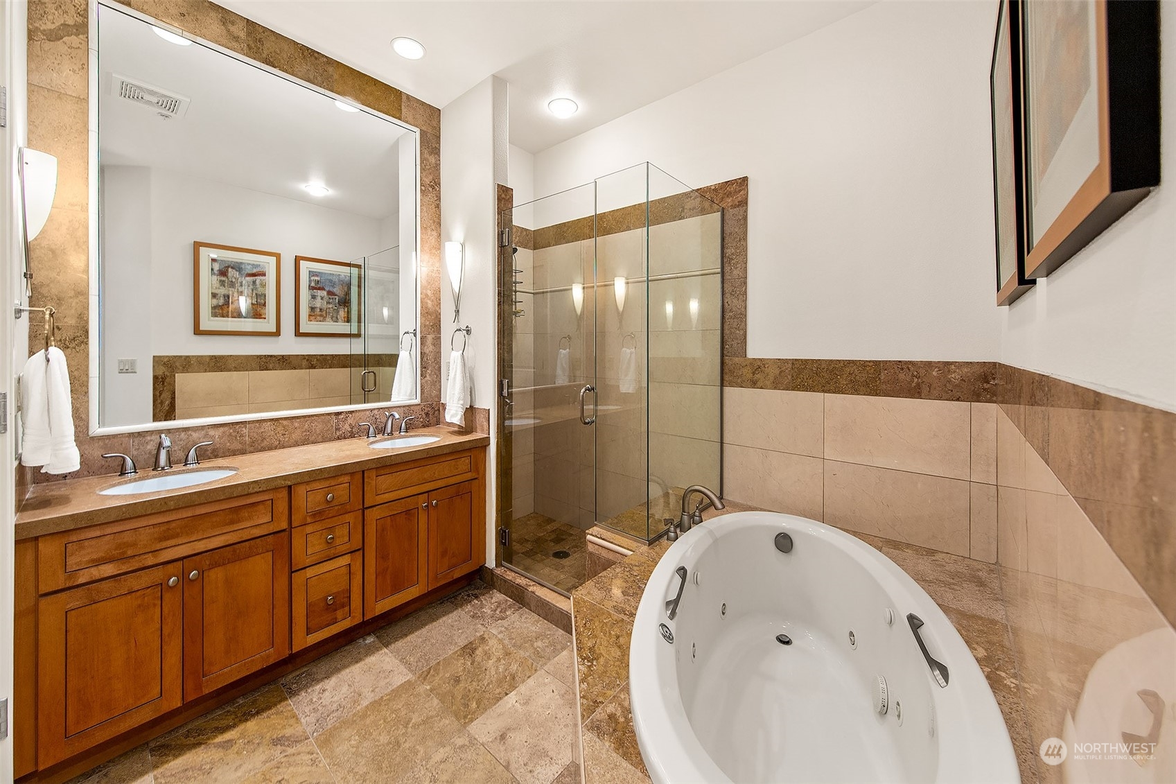 Primary bathroom offers a 5 piece bathroom with the jetted tub.  Toilet has its own room to the left of photo.  Vaulted ceilings throughout this home.