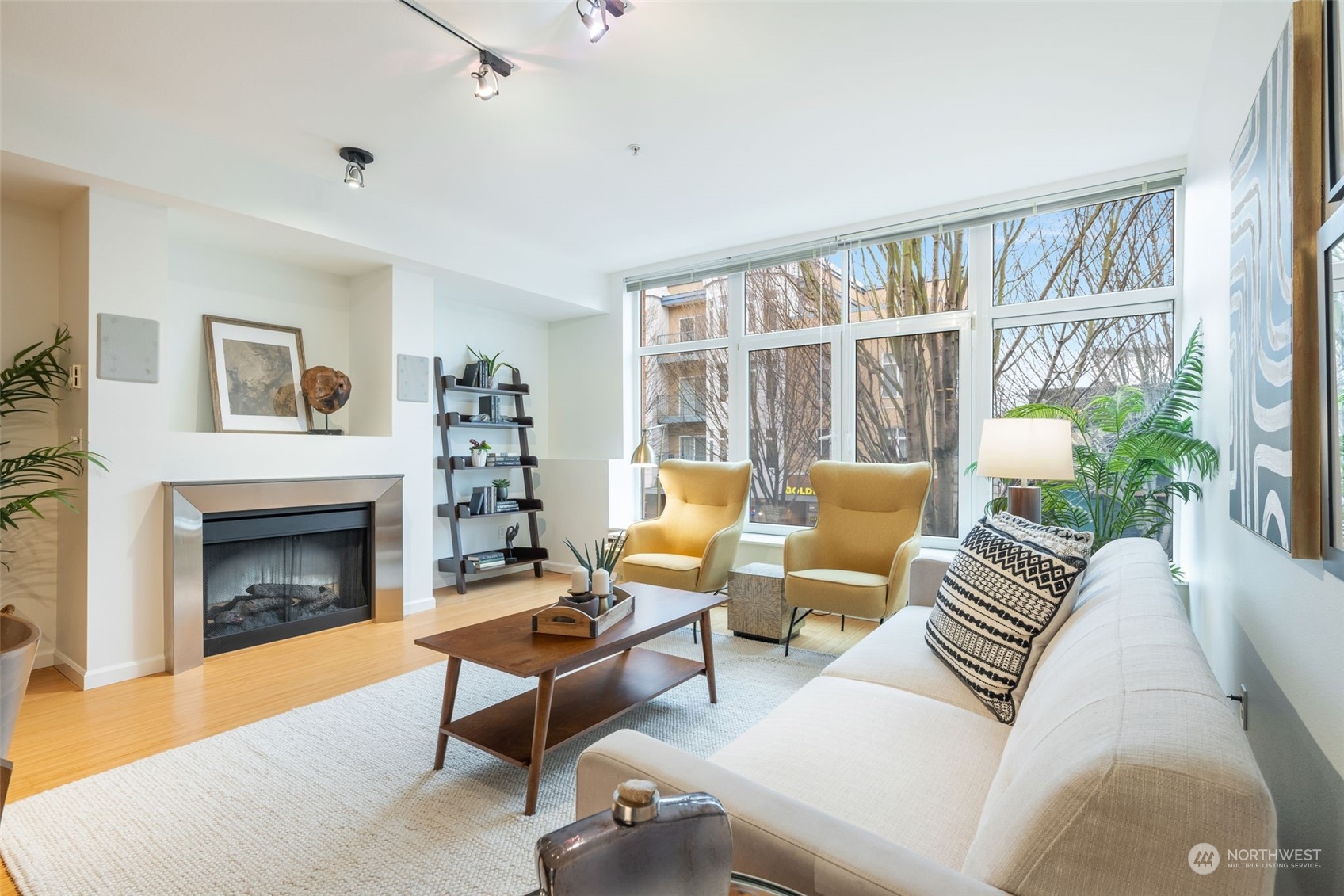 Spacious living room with an electric fireplace, tall ceilings, and large windows with a westerly outlook.