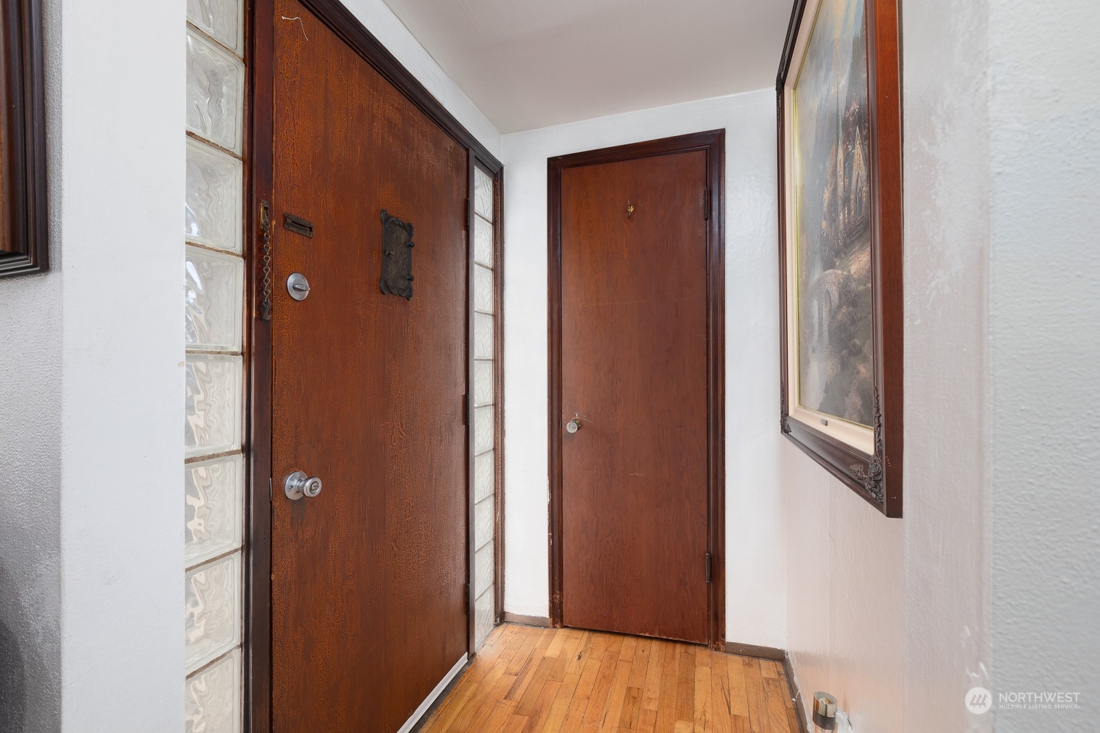 Nice entry door and hall closet. Features peek a book door and and glass block side windows. The original oak hardwood floors flow through into the living room. The covered porch helps keep the sun from hitting the door directly, which keeps it cooler.